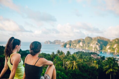 two women sitting on a hilltop