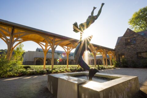 sculpture of a girl swimming with a dolphin at sunrise