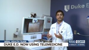 Neel Kapadia, MD standing in front of a computer with a camera which is used for telehealth visits