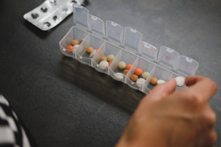 person about to place a pill in a pill organizer