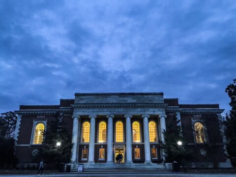 a building with gothic columns at twilight with lights shining through the windows