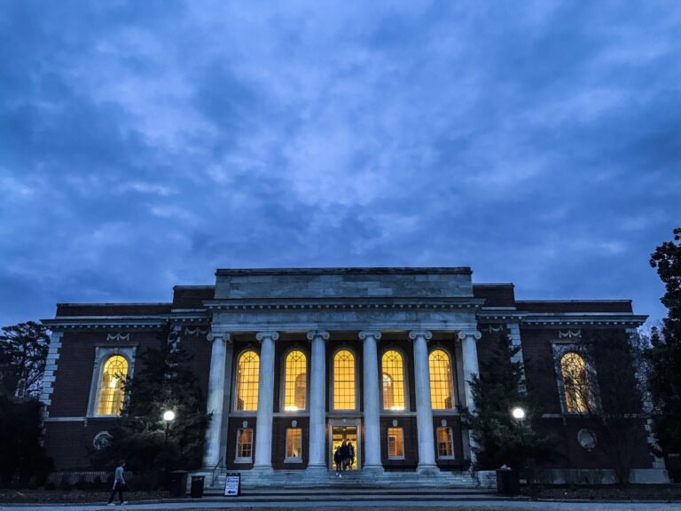 a building with gothic columns at twilight with lights shining through the windows