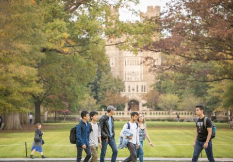 college students walking across campus during the fall with trees and the Duke Chapel in the background
