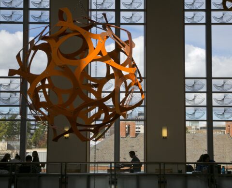 a modern, metal sculpture of interconnected arches forming a sphere hanging inside a building
