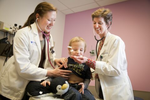 a young child blowing feathers out of a doctor's hand