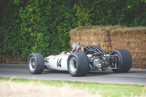 early model indy car in front of hay bale barrier